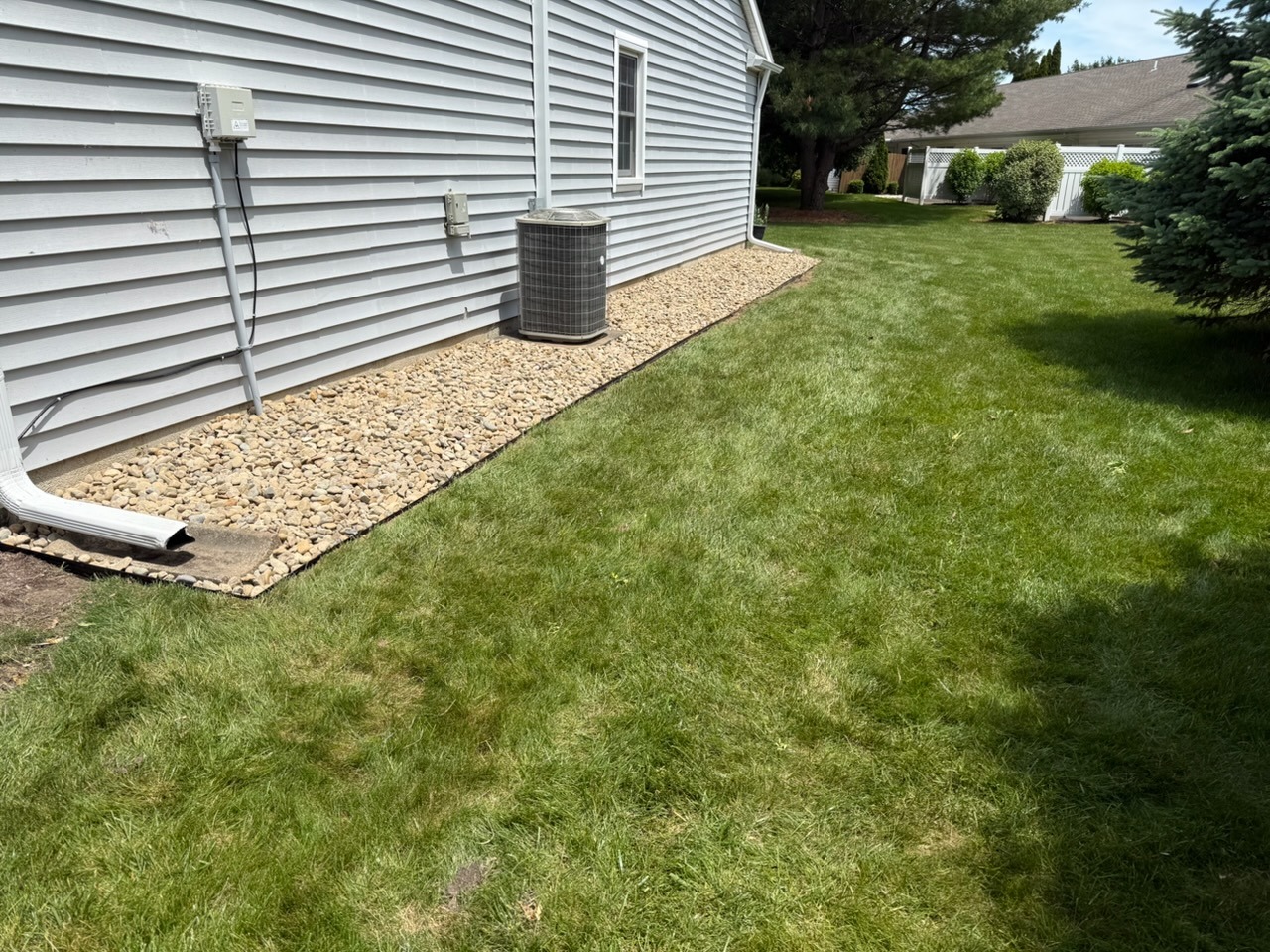 After Still Meadow’s side-yard stone-bed project, with clean landscape stone installed beside the house